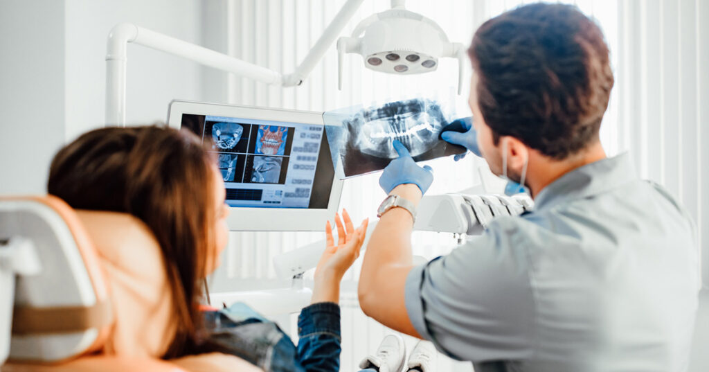 dentist showing teeth x-ray to patient at dental clinic office