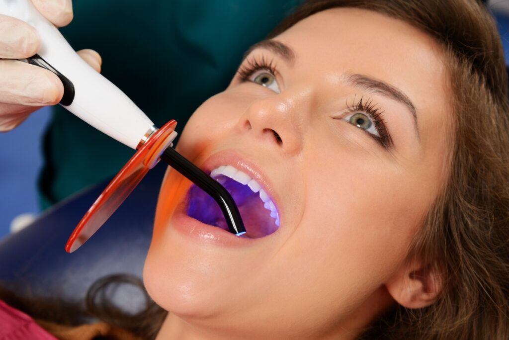 Young woman patient stopping treatment with dental UV light equi