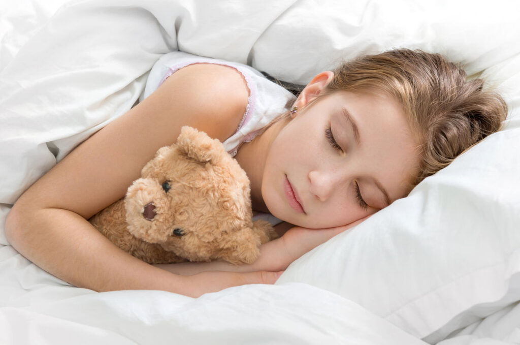 Amazing child napping and hugging her teddy bear in sleep, calm and peaceful