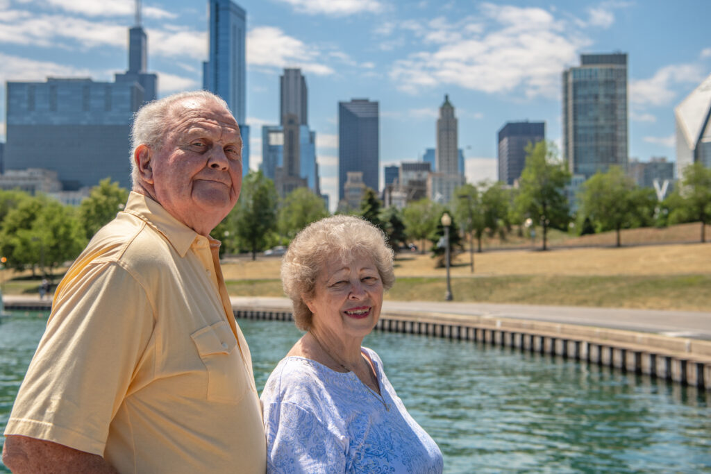 Portrait of a beautiful senior couple exploring the Lakefront Trail in Chicago, Illinois, with the city skyline and Lake Michigan beyond.
