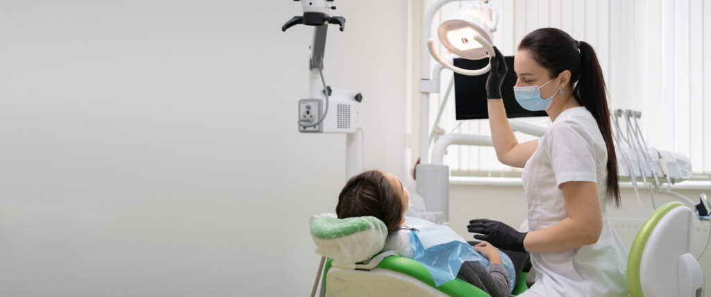 Caucasian woman dentist doctor in office with dental equipment microscope treats teeth to patient in chair. Place for your text. Medicine and dentistry concept.